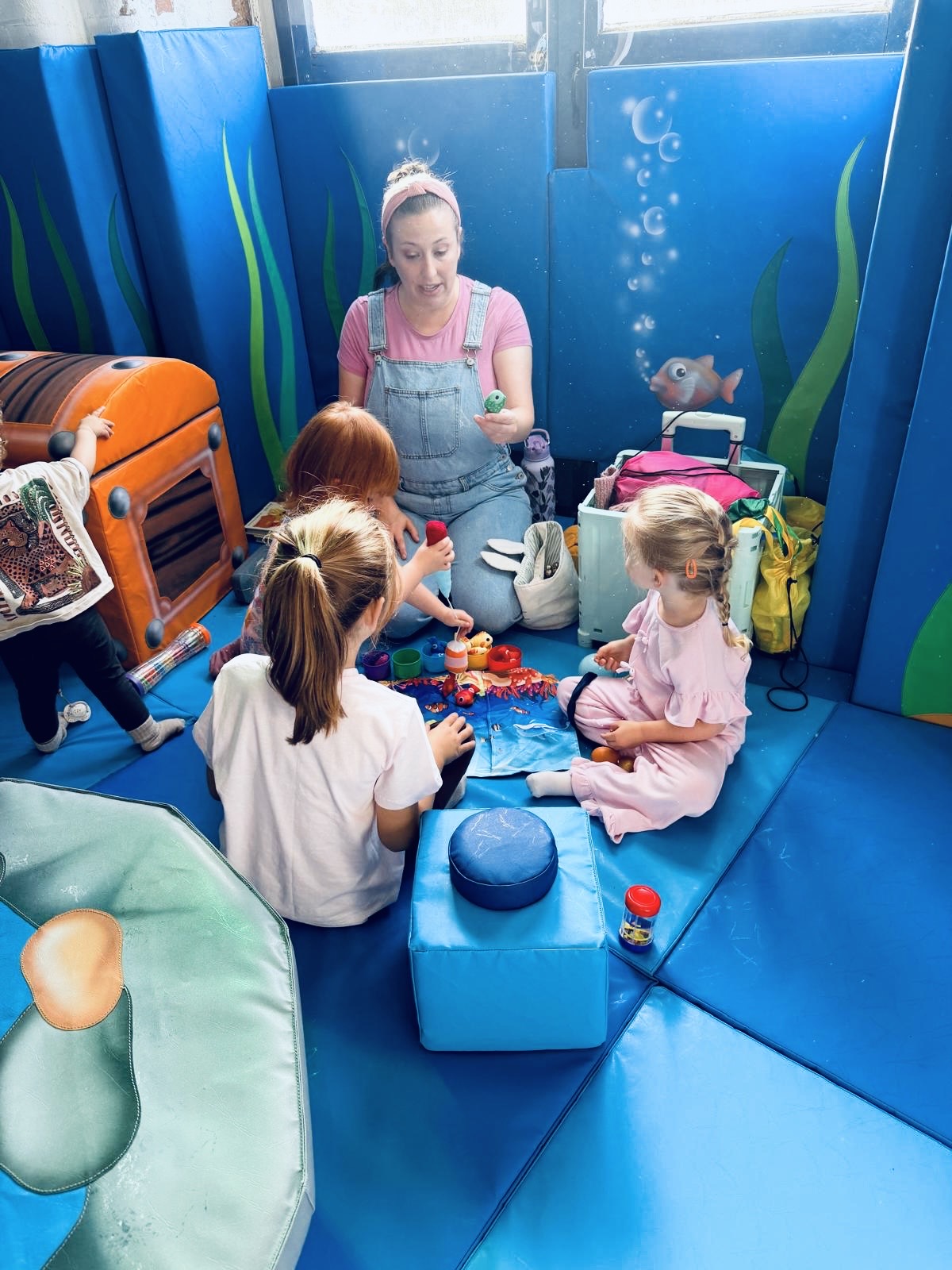 A sensory session at Little Harbour Club with toddlers playing on padded mats in an underwater themed room