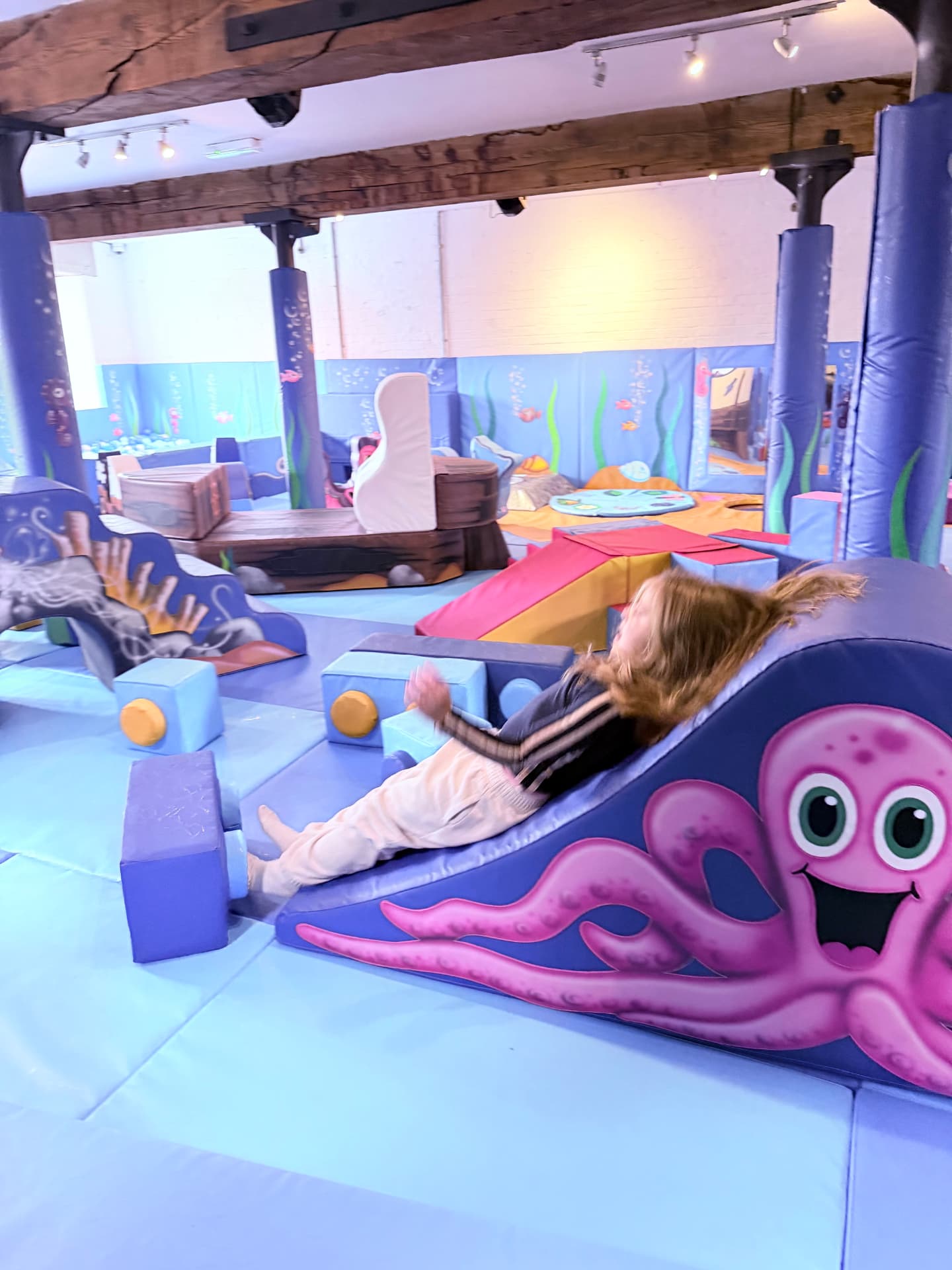 A child giggling on the octopus slide at Little Harbour Club soft play in Weymouth