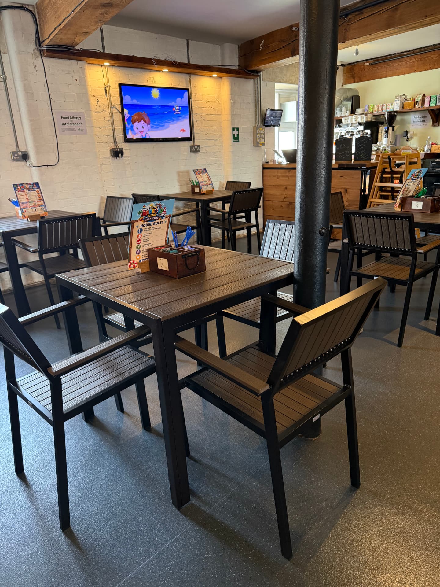 Café tables at Little Harbour Club with the coffee counter, TV and children's menus on the tables